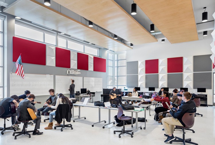 High school students playing musical instruments in large classroom