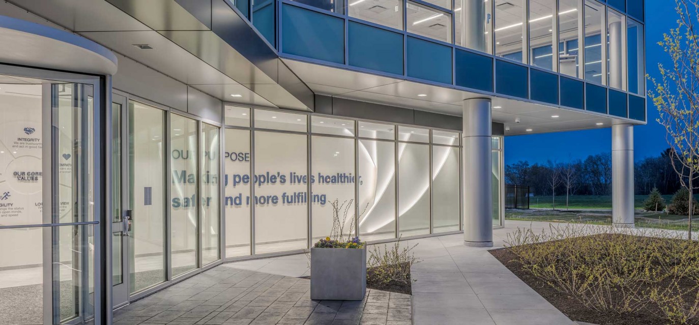 Glass entrance to new Olympus headquarters with welcoming view of interior