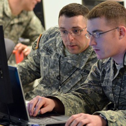 Two US Army servicemen looking at a laptop screen
